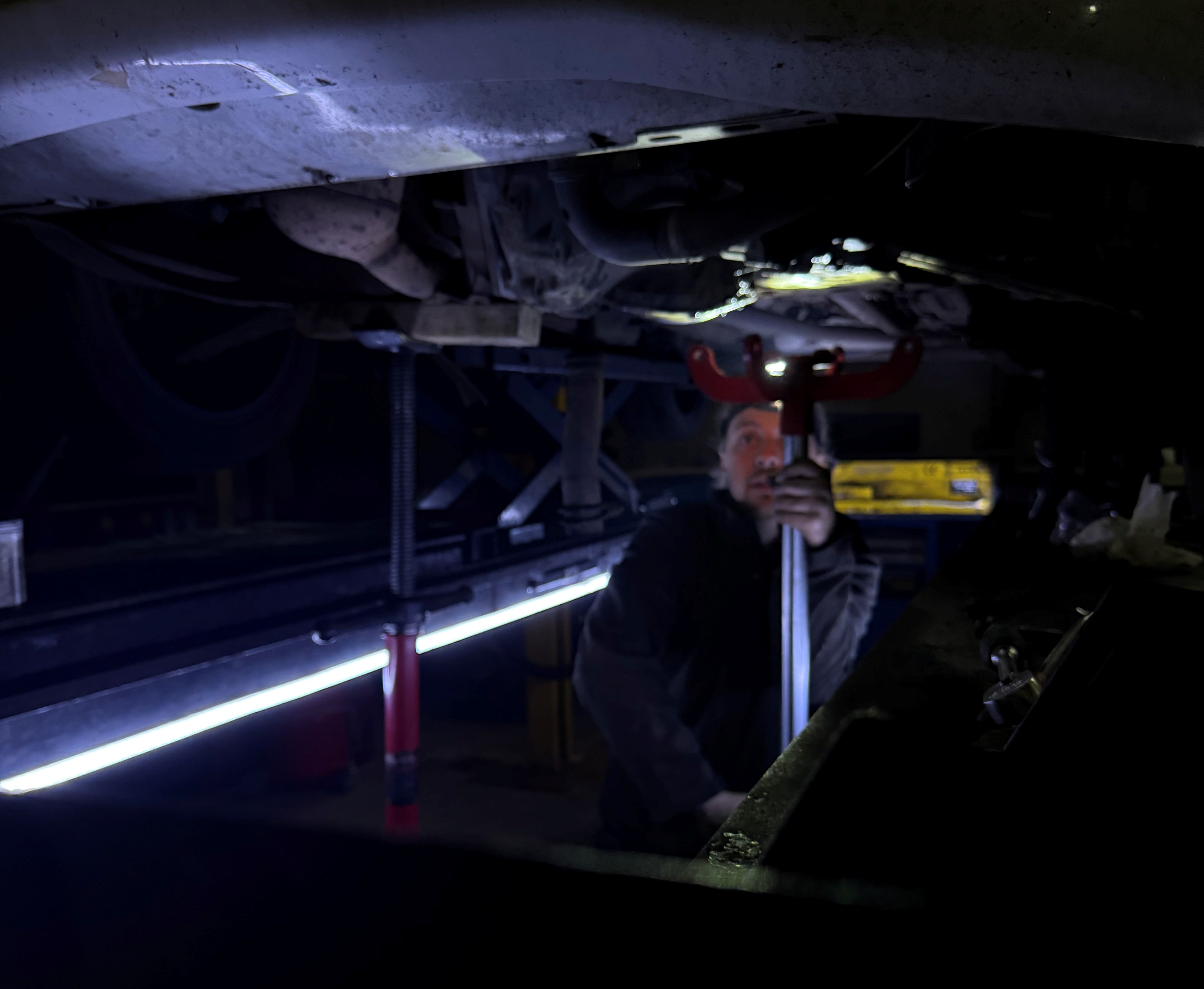 JR Auto Services employee standing next to a vehicle, which is currently being repaired.
